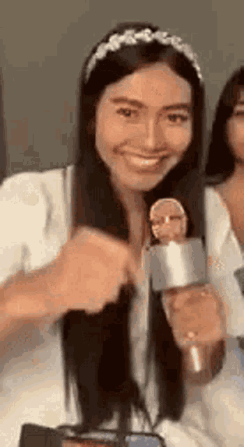 a woman is holding a microphone and smiling while wearing a headband .