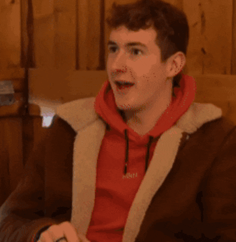 a blurry picture of a man in a red shirt sitting in a chair