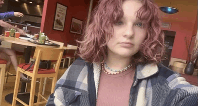 a girl with pink hair is taking a selfie