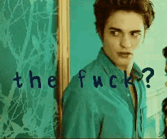 a man in a blue shirt is standing in front of a wall with the words the fuck written on it