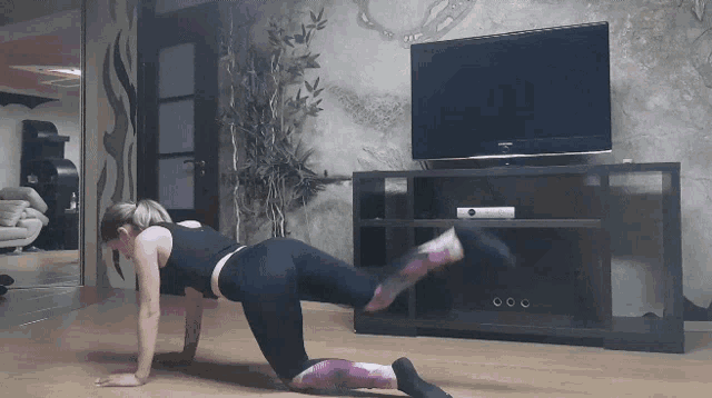 a woman doing exercises in front of a samsung television