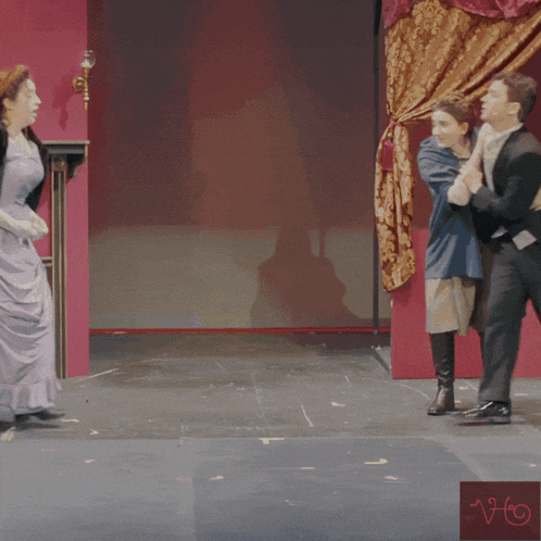 a man in a tuxedo and a woman in a purple dress are on a stage