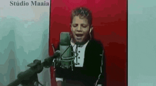 a young boy singing into a microphone in a studio .