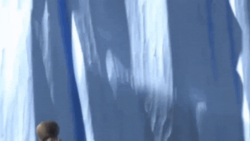 a person is standing in front of a large iceberg .