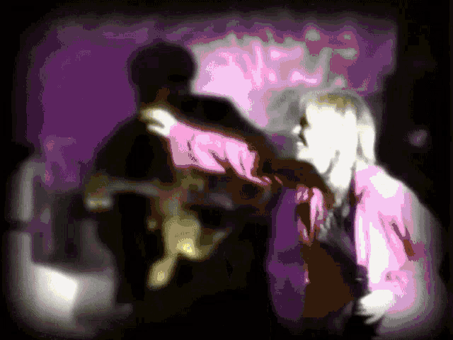 a woman in a pink jacket is standing in front of a man in a pink shirt