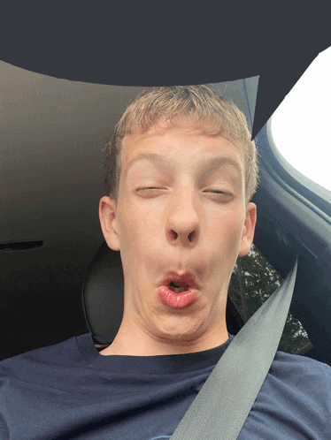 a young man making a funny face in a car