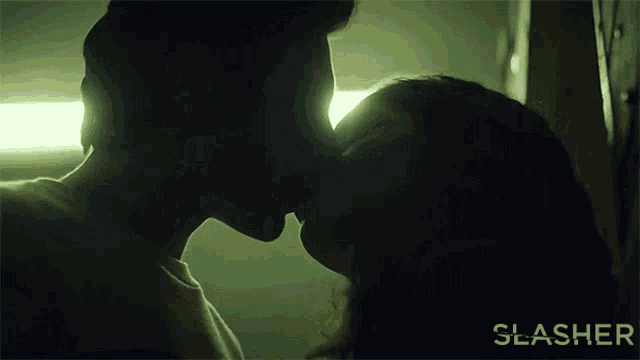 a man and a woman are kissing in a dark room with the word slasher on the bottom