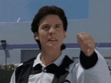 a man with his fist in the air is wearing a white shirt