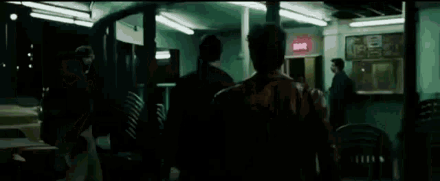a group of men are standing in a dark room with a pepsi sign .