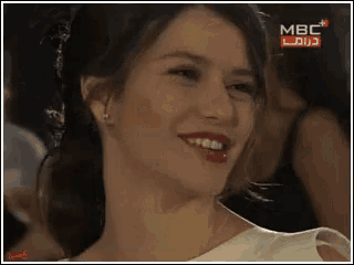 a woman in a white dress is smiling in front of a mbc sign