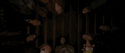 a group of people are sitting in a circle in a dark room looking up at the camera .