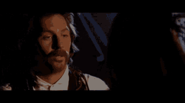 a man with a beard is looking at a woman in a dark room .