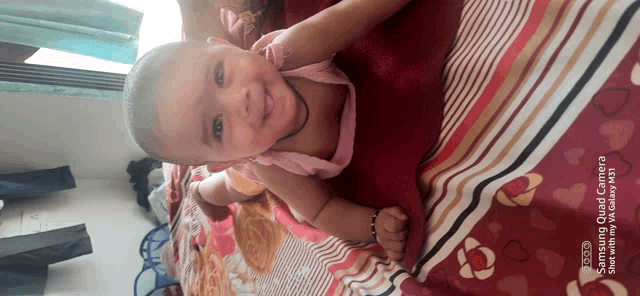 a baby is laying on a bed with a red and white striped blanket