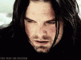 a close up of a man 's face with long black hair .