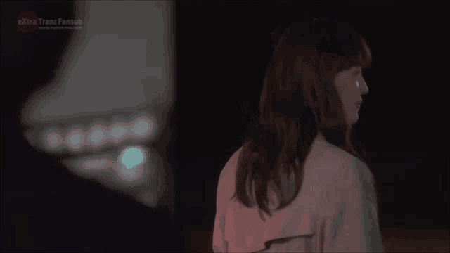 a woman stands in front of a sign that says extra transfansub
