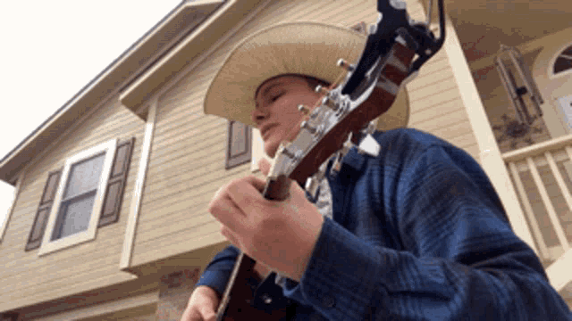 a man wearing a cowboy hat is playing a guitar