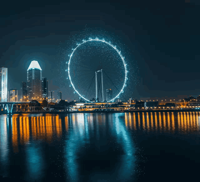 a large ferris wheel is lit up at night over a river