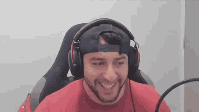a man wearing headphones and a baseball cap is sitting in a chair .