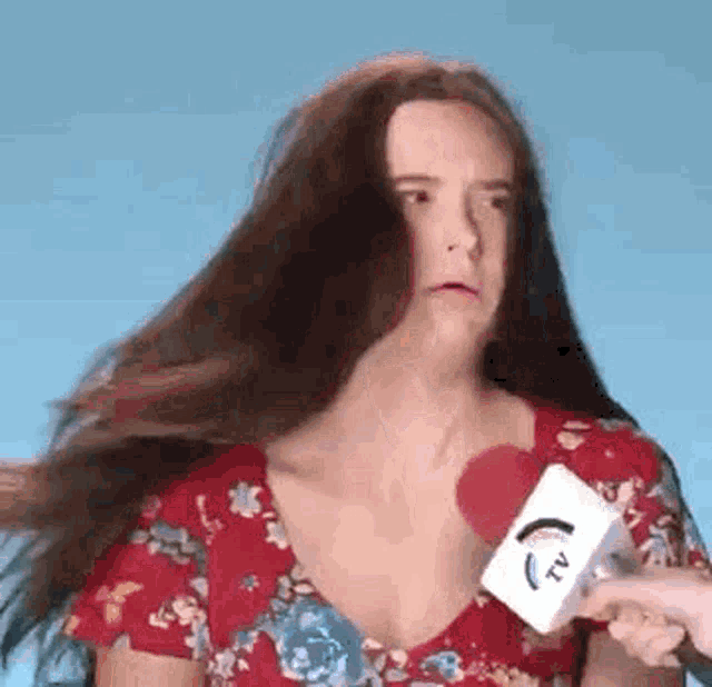 a woman in a red floral dress is holding a microphone .
