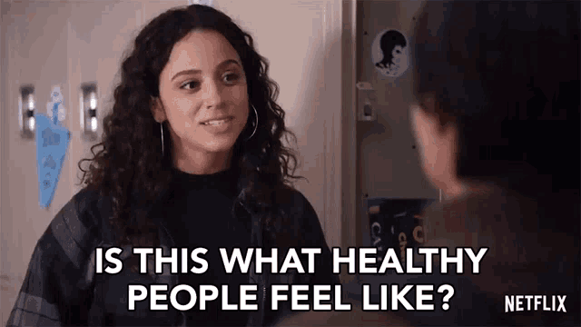 a woman with curly hair is talking to another woman in a hallway .