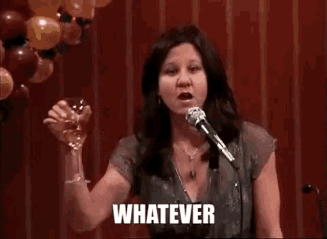 a woman is holding a glass of wine in front of a microphone and says whatever .