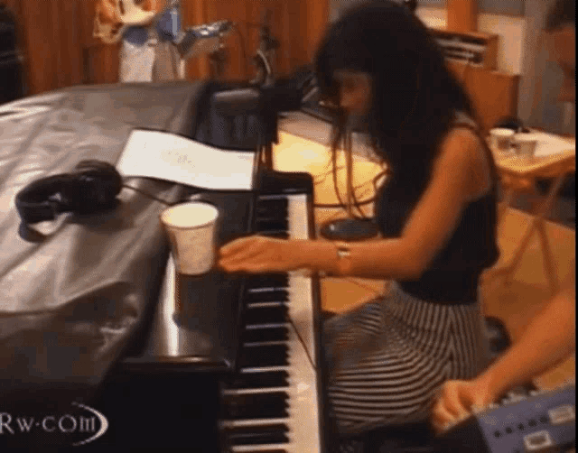 a woman is playing a piano in a room with the word rw on the bottom right
