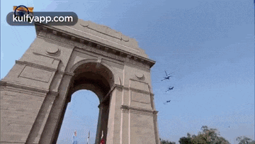 a group of helicopters are flying over a monument in front of a building .