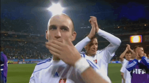 a group of soccer players are applauding and one of them is wearing a fifa jersey