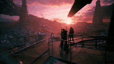a couple standing on a balcony looking at a sunset