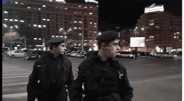 two police officers are walking down a street at night in front of a dentalmed sign