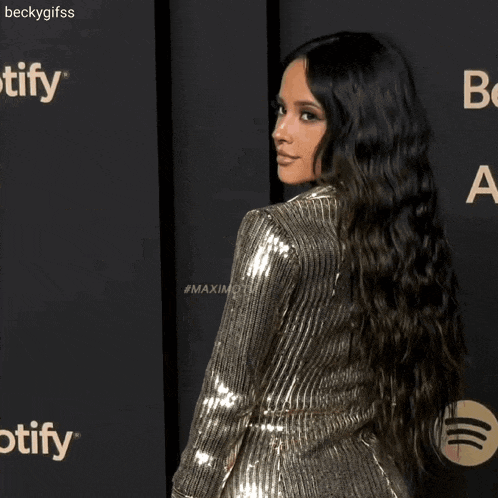 a woman in a sequined dress is smiling and dancing on a red carpet .