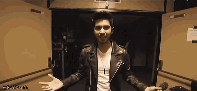 a man in a black leather jacket is standing in a hallway