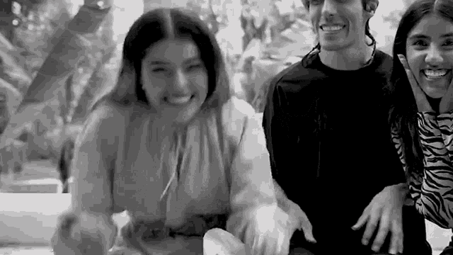 a man and two women are sitting next to each other and smiling for a picture .