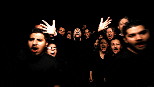 a group of people are screaming in the dark with their hands in the air