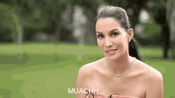 a woman wearing a necklace and a strapless dress says muachh .