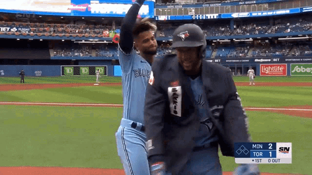 a blue jays player stands on the field with a referee