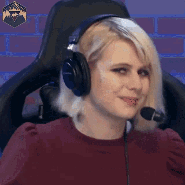 a woman wearing headphones and a microphone is sitting in a chair and smiling .