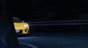 a yellow sports car is driving down a dark road .