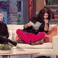 a woman sits on a couch reading a book while a man sits behind her