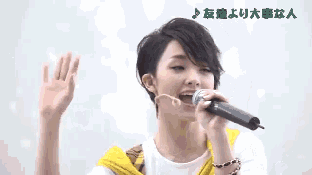 a woman singing into a microphone with foreign writing on the bottom