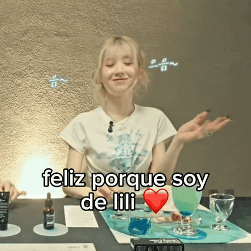 a woman sitting at a table with a heart and the words feliz porque soy de lili on the bottom