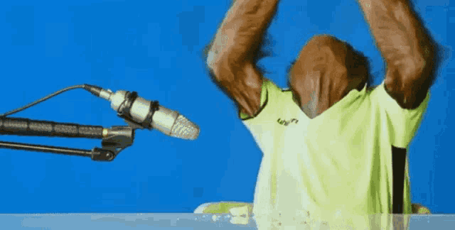 a monkey in a neon green shirt is standing in front of a microphone