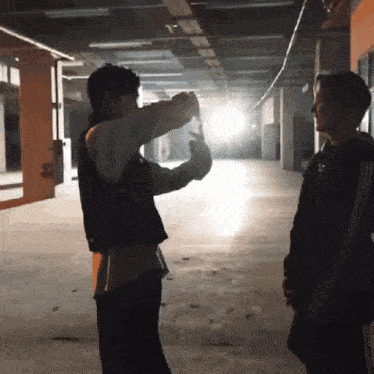 a man is taking a picture of another man in a dark hallway