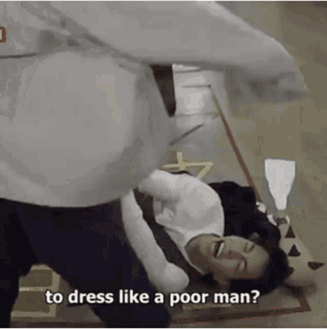 a man is laying on the floor and laughing while another man throws a punch at him .