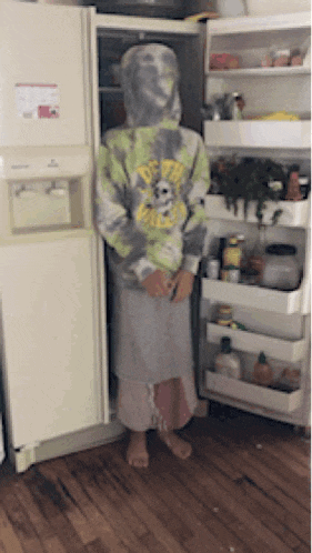 a person wearing a tie dye hoodie standing in front of an open refrigerator