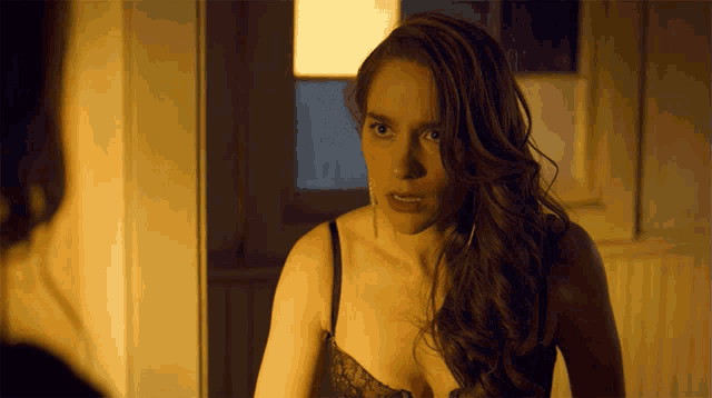 a woman in a bra looks at herself in a mirror
