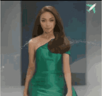 a woman in a green dress is walking down the runway