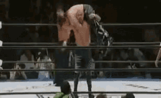 a man is wrestling another man in a wrestling ring with a crowd watching .