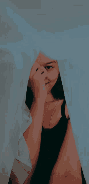 a woman is hiding her face behind a curtain .