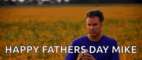 a man in a purple shirt is holding a can of beer in front of a field .